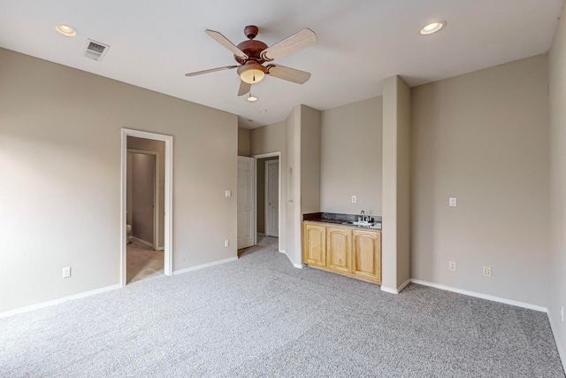 unfurnished bedroom featuring ceiling fan, light colored carpet, connected bathroom, and sink