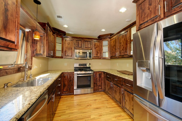 kitchen featuring pendant lighting, sink, appliances with stainless steel finishes, and light hardwood / wood-style floors