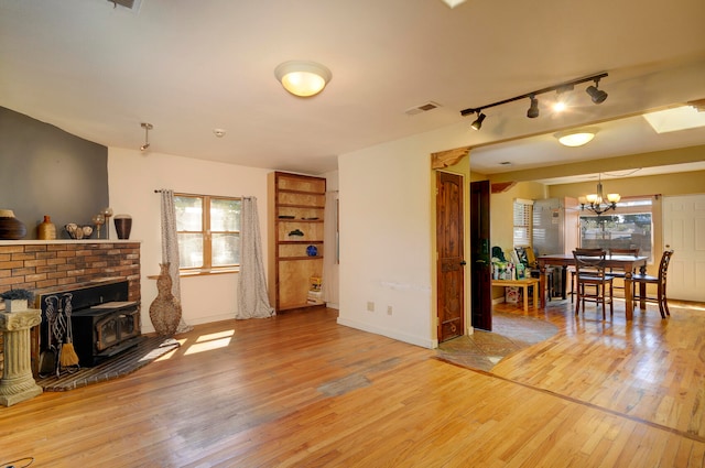 living room with a brick fireplace, a notable chandelier, hardwood / wood-style floors, and track lighting