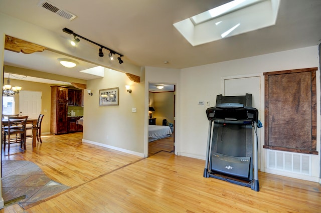 interior space with a chandelier, light hardwood / wood-style floors, a skylight, and rail lighting