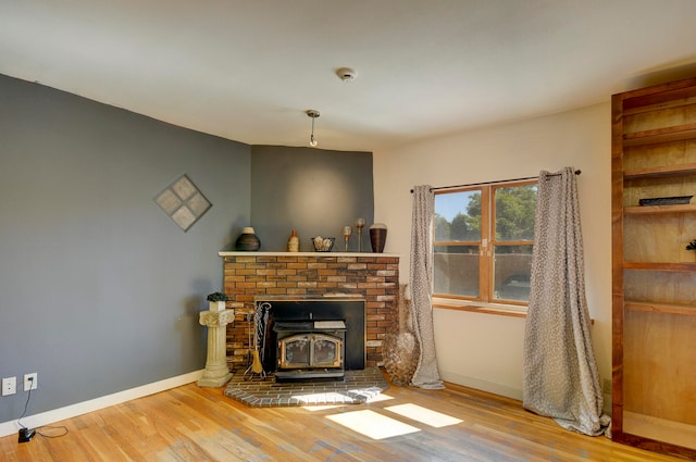 living room with a wood stove, wood-type flooring, and a brick fireplace