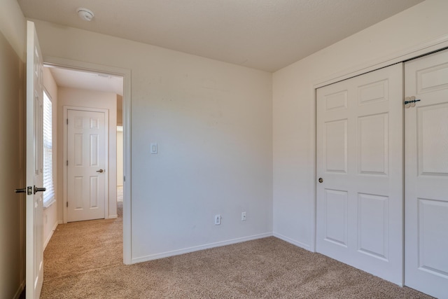 unfurnished bedroom with a closet and light colored carpet