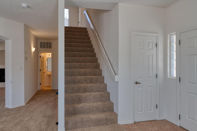 carpeted entryway with a textured ceiling