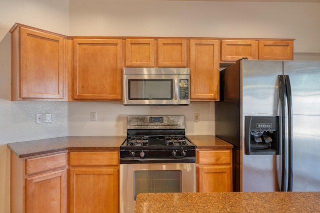 kitchen with stainless steel appliances, dark stone counters, and backsplash