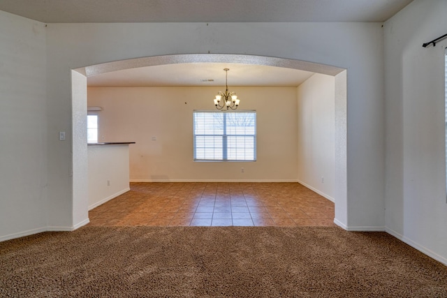 spare room featuring a healthy amount of sunlight, a chandelier, and carpet