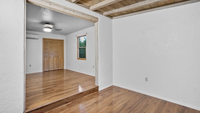 unfurnished room featuring wooden ceiling, wood-type flooring, beam ceiling, and an AC wall unit