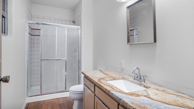 bathroom featuring wood-type flooring, vanity, toilet, and a shower with door