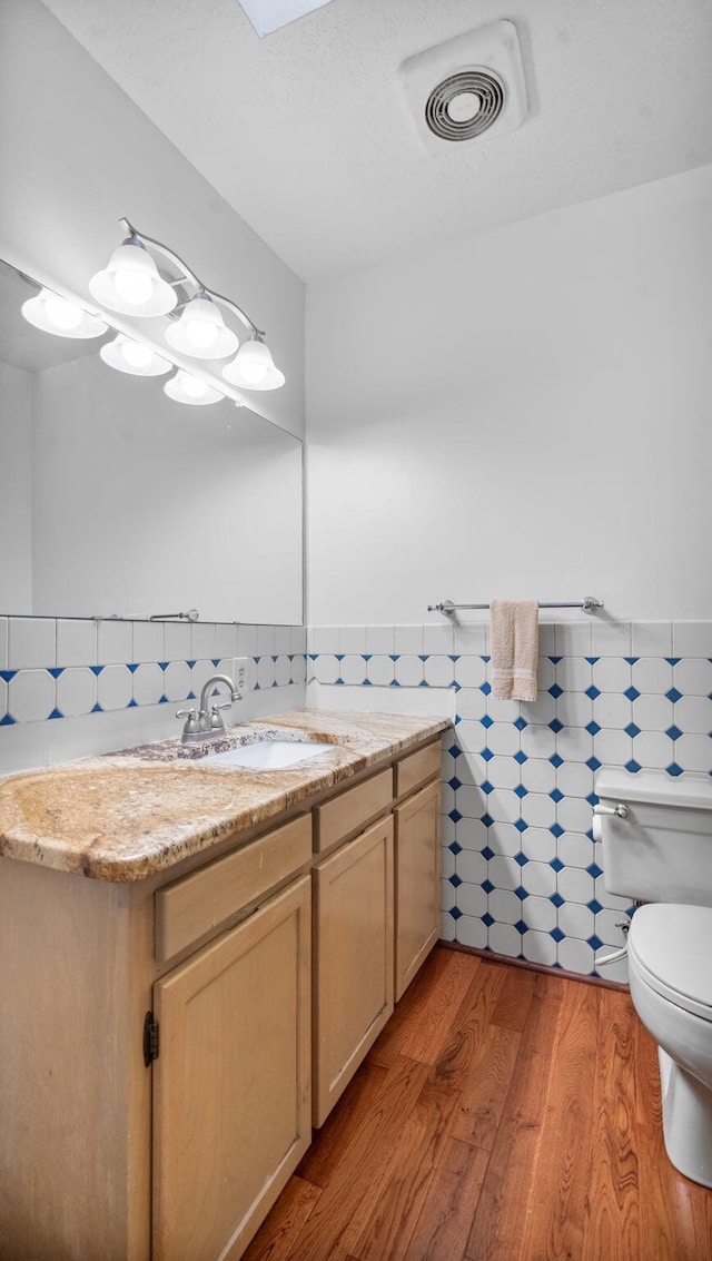 bathroom with vanity, tile walls, toilet, and hardwood / wood-style flooring