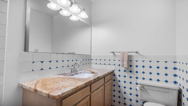 bathroom with tile walls, vanity, and toilet