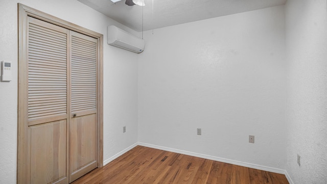 unfurnished bedroom featuring a closet, ceiling fan, hardwood / wood-style flooring, and a wall mounted AC