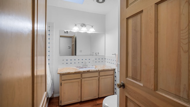 bathroom featuring wood-type flooring, vanity, backsplash, and toilet