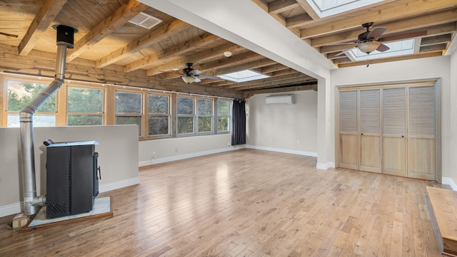 unfurnished living room featuring light wood-type flooring, a skylight, ceiling fan, and a wall mounted air conditioner