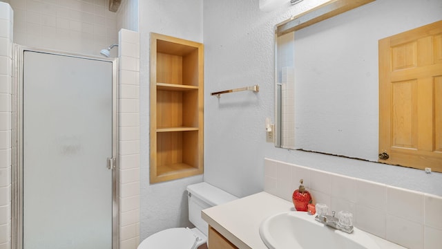 bathroom with toilet, tasteful backsplash, a shower with shower door, vanity, and built in features