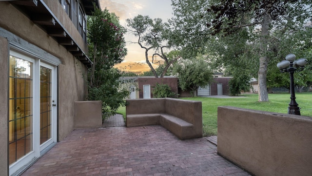 patio terrace at dusk featuring a lawn