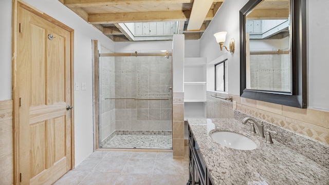 bathroom featuring tile walls, vanity, beamed ceiling, a shower with door, and tile patterned floors