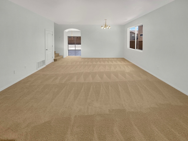 carpeted spare room featuring an inviting chandelier