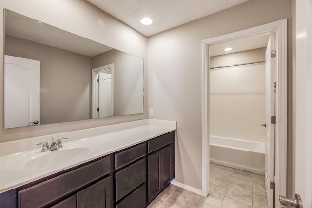 bathroom with tile patterned floors, a textured ceiling, shower / washtub combination, and vanity