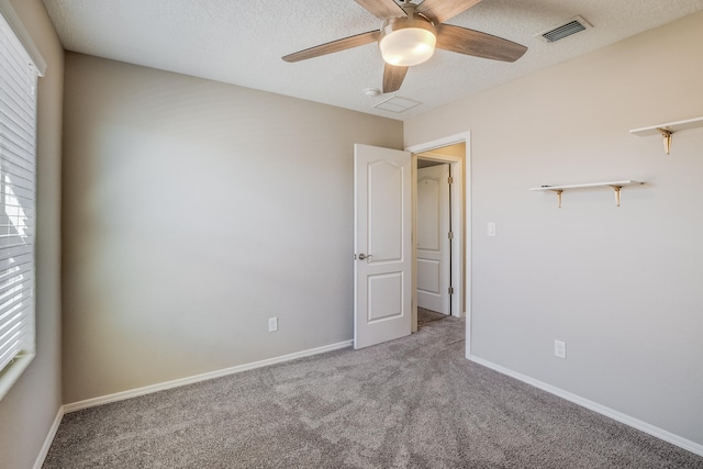 carpeted empty room featuring ceiling fan and a textured ceiling