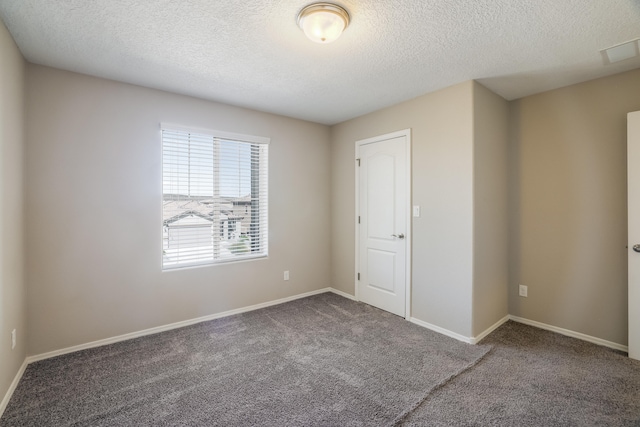 carpeted empty room with a textured ceiling