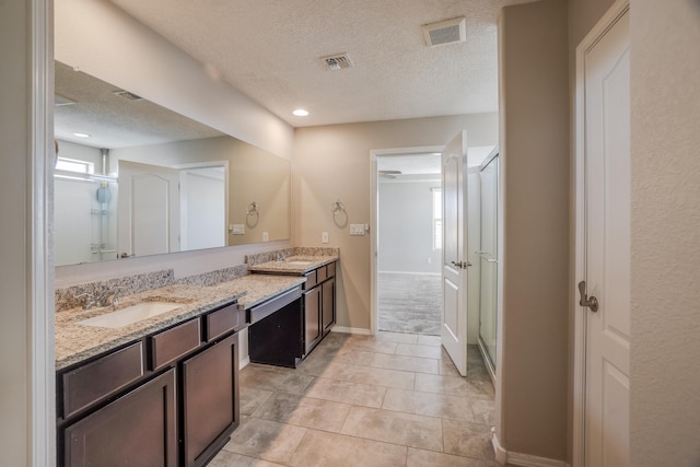 bathroom with vanity, a textured ceiling, tile patterned flooring, and an enclosed shower