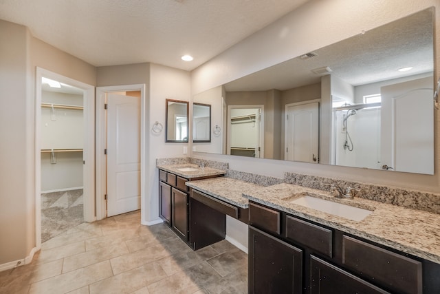 bathroom with a textured ceiling, tile patterned flooring, vanity, and an enclosed shower