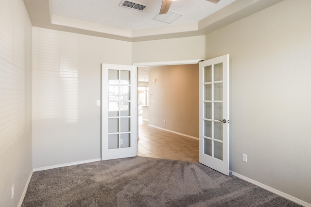 carpeted spare room with french doors, a textured ceiling, and ceiling fan