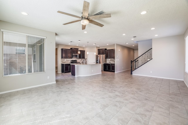 unfurnished living room featuring a textured ceiling, sink, and ceiling fan