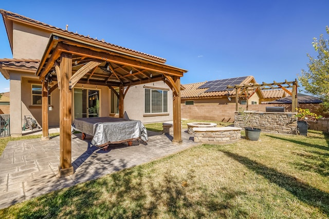 back of house featuring a gazebo, a lawn, a patio area, and a hot tub