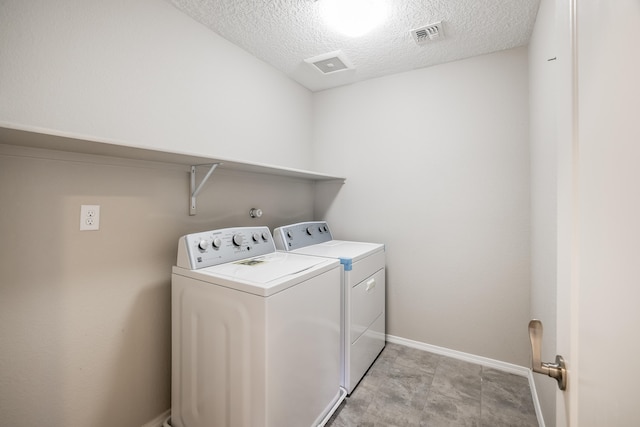 clothes washing area featuring a textured ceiling and washing machine and dryer