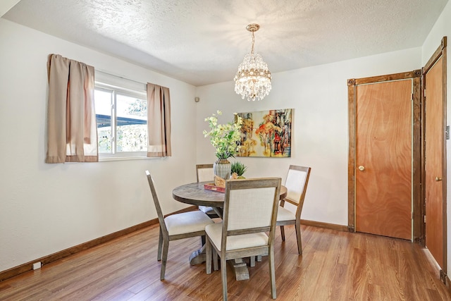 dining area featuring an inviting chandelier, a textured ceiling, and light hardwood / wood-style floors