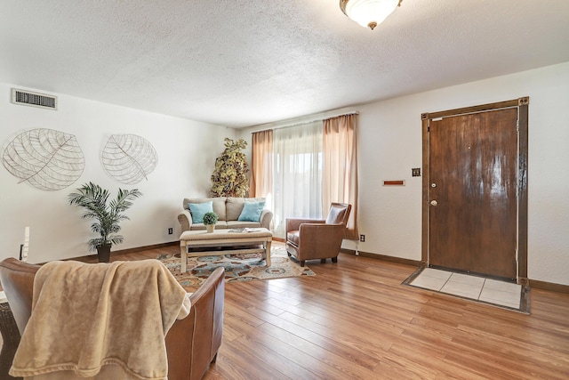 living room with a textured ceiling and light hardwood / wood-style floors