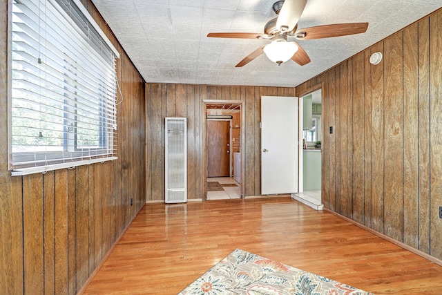 spare room with ceiling fan, wooden walls, and light hardwood / wood-style floors