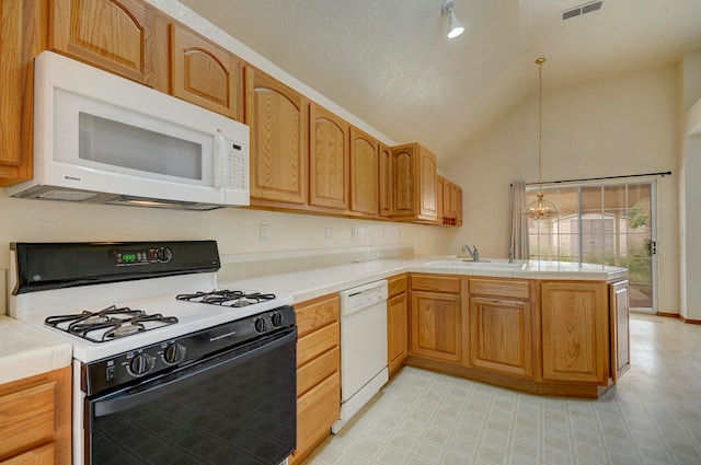 kitchen with white appliances, sink, kitchen peninsula, decorative light fixtures, and tile counters