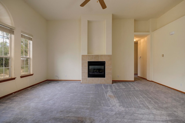 unfurnished living room featuring carpet floors, a tile fireplace, and ceiling fan