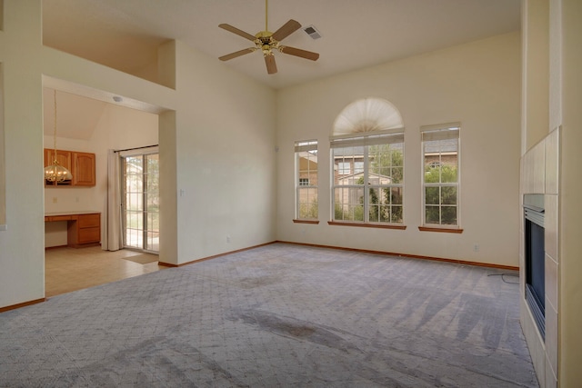 unfurnished living room featuring light carpet, high vaulted ceiling, and ceiling fan with notable chandelier