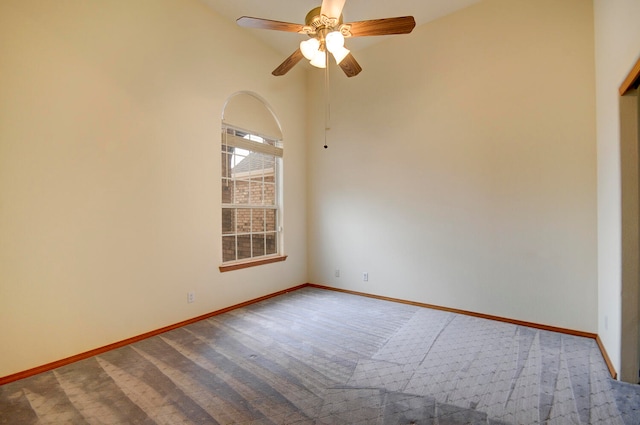 empty room with carpet floors, a towering ceiling, and ceiling fan