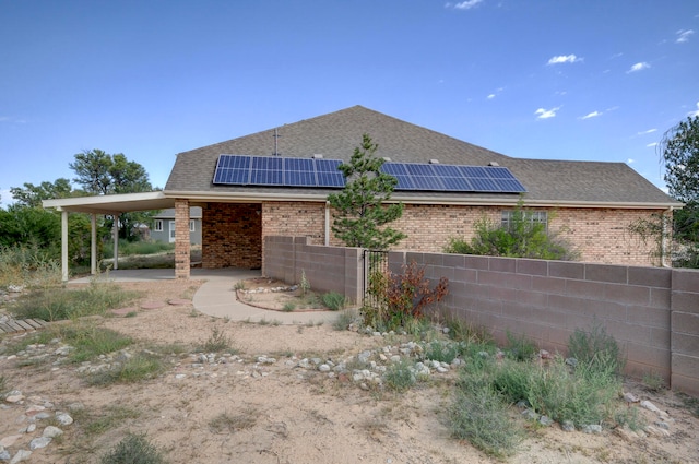 back of house featuring solar panels and a carport