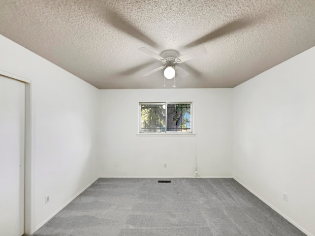 empty room with ceiling fan, carpet floors, and a textured ceiling