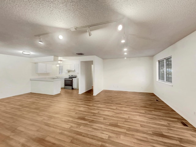 unfurnished living room featuring a textured ceiling, light hardwood / wood-style floors, and track lighting