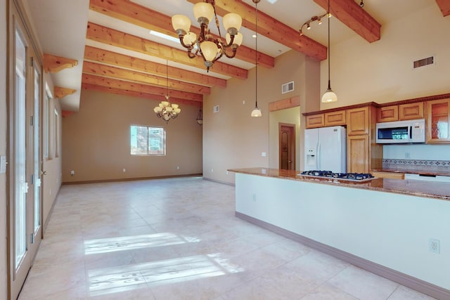 kitchen featuring light stone counters, hanging light fixtures, white appliances, and a notable chandelier