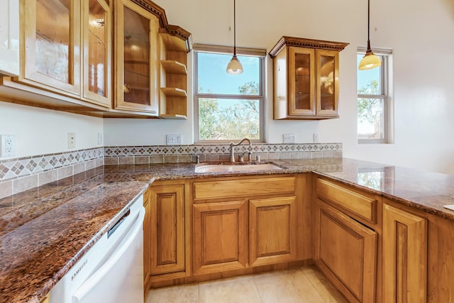 kitchen with sink, dark stone countertops, white dishwasher, decorative light fixtures, and light tile patterned floors