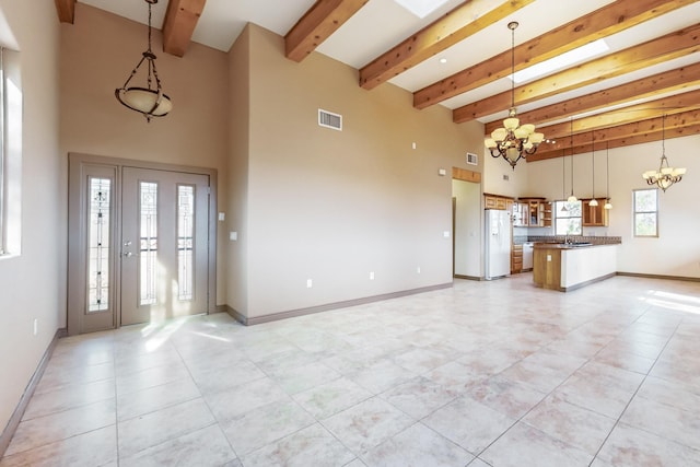 interior space featuring beamed ceiling, a notable chandelier, a towering ceiling, and a wealth of natural light