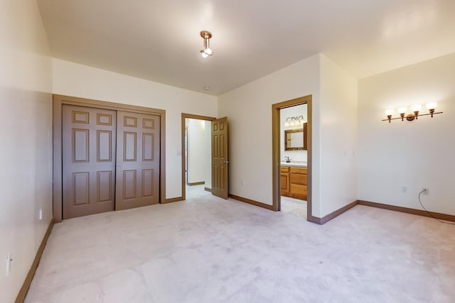 unfurnished bedroom featuring light carpet, a closet, and ensuite bathroom