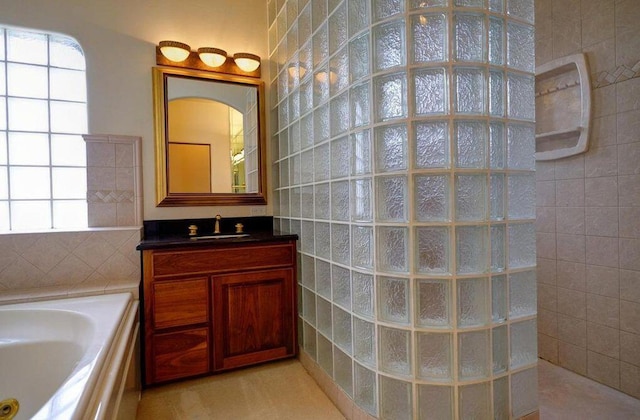 bathroom featuring vanity, a healthy amount of sunlight, and a tub to relax in