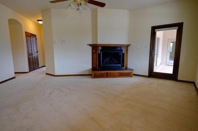280 Angel Rd, Corrales, NM 87048 - unfurnished living room featuring ceiling fan, light colored carpet, arched walkways, and a fireplace with raised hearth