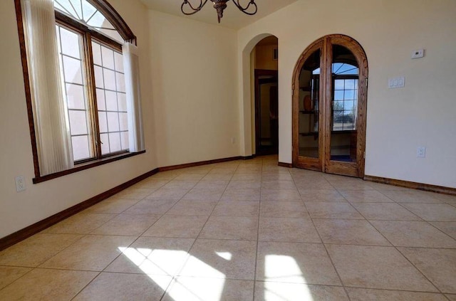 spare room with light tile patterned floors, plenty of natural light, and a notable chandelier