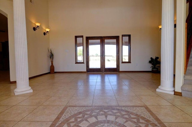 tiled foyer entrance with french doors, ornate columns, and a high ceiling