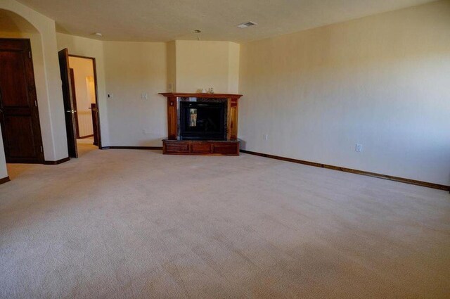 280 Angel Rd, Corrales, NM 87048 - unfurnished living room with light colored carpet, a glass covered fireplace, and arched walkways
