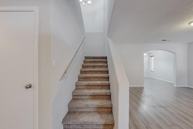 staircase with a textured ceiling and hardwood / wood-style floors