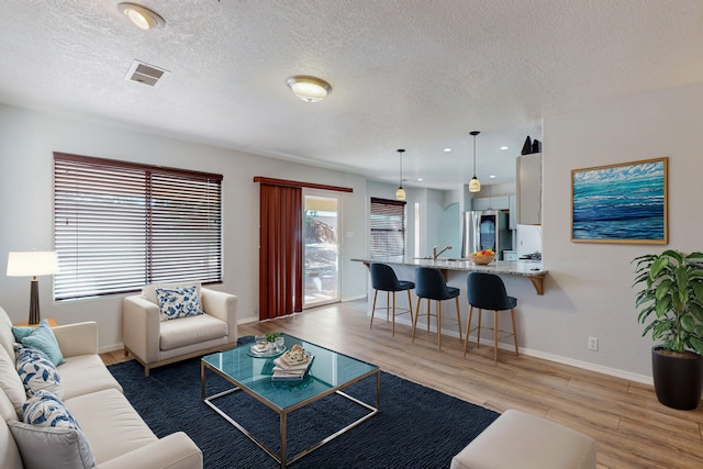 living room featuring light hardwood / wood-style floors, sink, and a textured ceiling